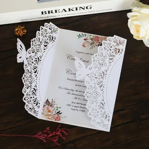Primo piano di invito a nozze bianco tagliato al laser con dettagli eleganti di farfalla.