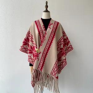 Detailed view of an ethnic knit poncho with red tribal patterns and tassels.