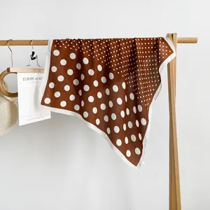 Vintage bruine zijden vierkante sjaal met witte stippen hangend aan een houten rek