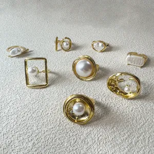 Vue détaillée de bagues dorées vintage avec perles élégantes sur surface en pierre