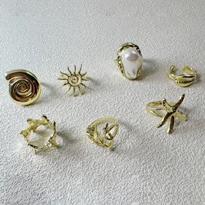 Vue détaillée de bagues vintage dorées avec perles baroques et motifs nautiques