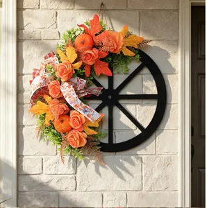 Handcrafted autumn wheel wreath with pumpkins and roses hanging on a textured brick wall