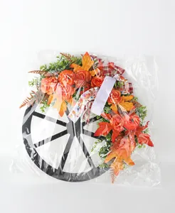 Autumn harvest decorative wreath with wooden wheel and pumpkins in clear plastic packaging