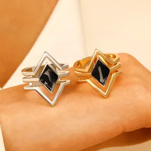 Close-up of multi-layer rhombus rings in gold and silver with black enamel.