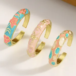 Detailed close-up showing vintage gold alloy open rings with colorful enamel floral patterns