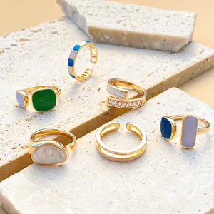 Collection of colorful enamel geometric rings displayed on a warm stone surface
