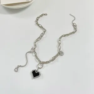 Detailed view of punk silver chain necklace with black rhinestone heart and Good Luck tag