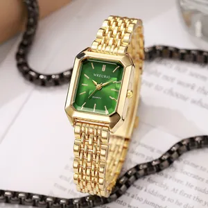 Close-up of elegant gold rectangular ladies watch with green dial and steel strap