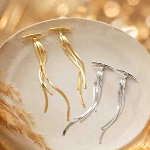 Detailed view of long tassel earrings with sleek gold and silver snake chains.