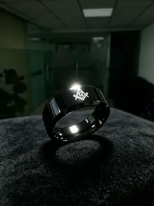 Close-up view of a polished black titanium steel ring with an engraved Freemasonry logo