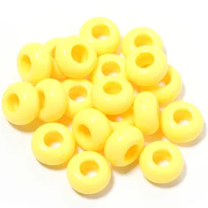 Macro dettaglio di perle in acrilico giallo da 13mm con grandi fori per gioielli fai-da-te.