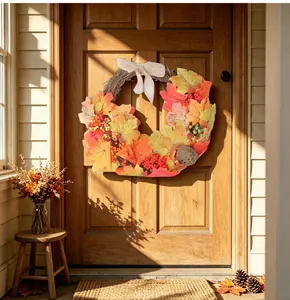 Detailed view of an autumn maple leaf wreath hanging on a rustic wooden front door.