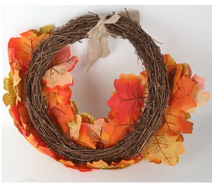 Close-up detail of autumn thanksgiving wreath featuring vibrant orange maple leaves and burlap bow