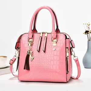 Close-up view showing the glossy pink crocodile texture and gold cat charm on handbag