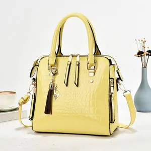 Stylish yellow crocodile pattern patent leather handbag with tassel charm shown in setting