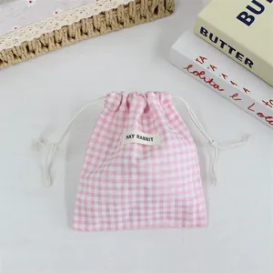 Détail d'une pochette à cordon à carreaux rose et blanc avec étiquette May Rabbit