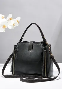 Dettaglio di una borsa a secchiello nera da donna alla moda con cerniere dorate.