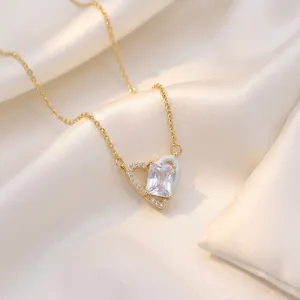 Elegant gold heart pendant necklace with zircon stones on soft silk background