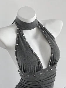 Detalle de un vestido halter gris con escote en V profundo y tachuelas plateadas.