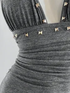 Primer plano de los remaches metálicos y la tela gris fruncida del vestido halter