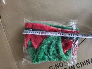 Detail view showing width measurement of a green and red plush Christmas elf hat