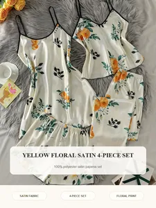 Detailed view of women's yellow floral print 4-piece satin pajama set laid on a rug.