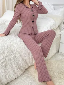 Close-up of a pink ribbed two-piece pajama set with black bow buttons