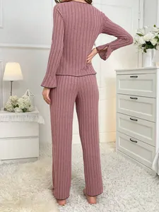 Back view of pink ribbed pajama set showing flared cuffs and cozy home bedroom setting