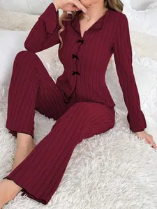 Close-up view of a burgundy ribbed two-piece pajama set featuring elegant black bow accents