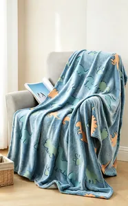 Manta de franela azul claro con estampados de dinosaurios colocada sobre un sillón gris