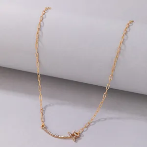 Detail of golden shooting star necklace with pavé crystal curved bar and paperclip chain.