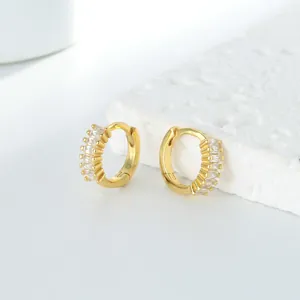 Détail de boucles d'oreilles créoles huggie plaquées or avec zircons baguette élégants