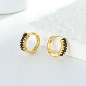Détail macro de boucles d'oreilles créoles dorées avec sertissage de zircons noirs baguette