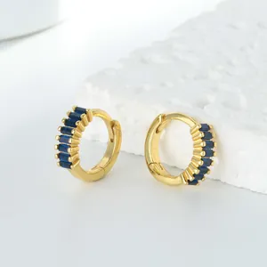 Gros plan détaillé de boucles d'oreilles créoles dorées avec d'élégantes pierres bleues baguette