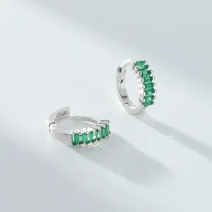 Gros plan sur des créoles en argent 925 minimalistes avec zircons verts baguette