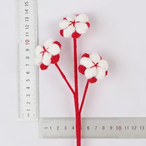 Close-up of handmade crochet red and white flower branch showing size with metal rulers