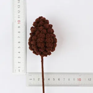 Detailed view of handmade knitted brown pinecone on a stick with measurement rulers