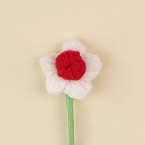 Detailed macro shot of a handmade red and white crochet flower decoration with stem