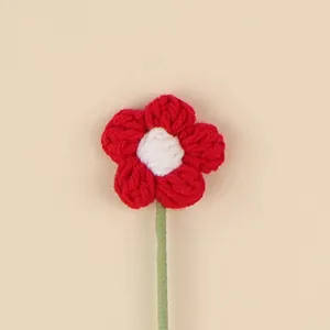 Macro view of a handmade red and white crochet flower accessory with a green stem