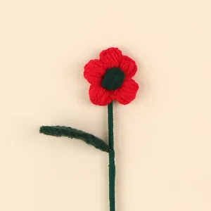 Close-up detail of a handmade red and green crochet wool flower branch with soft yarn texture