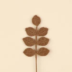 Detailed view of a hand-crocheted brown leaf branch for Christmas floral arrangements
