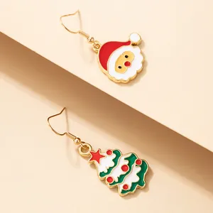 Détail rapproché de boucles d'oreilles de Noël asymétriques en émail avec Père Noël.