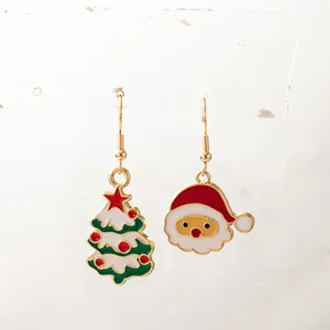 Gros plan sur les boucles d'oreilles asymétriques sapin de Noël et Père Noël en émail