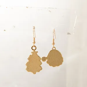 Détail de boucles d'oreilles sapin de Noël et bonnet de Père Noël dorées avec dos texturé.