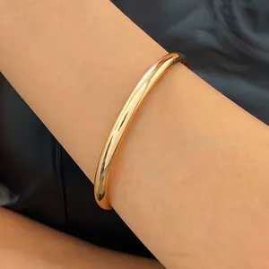 Detailed macro view of a minimalist gold-plated alloy bangle with a polished smooth surface finish