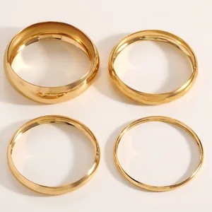 Detailed view of four golden smooth surface bangles in various widths, alloy jewelry.