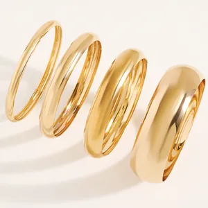 Close-up detail of high-polish gold alloy bangles showing varied widths and smooth finish