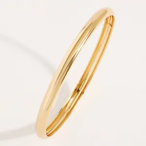 Detailed view of a polished gold-finish metal bangle with a smooth reflective surface