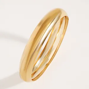 Macro view of a classic gold polished wide bangle showing reflective metallic finish
