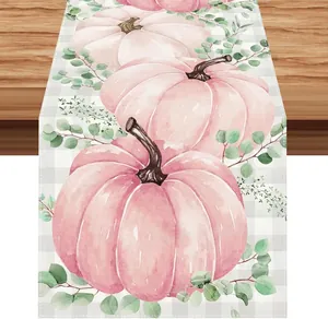 Gros plan d'un chemin de table en lin avec citrouilles roses et jolies feuilles vertes